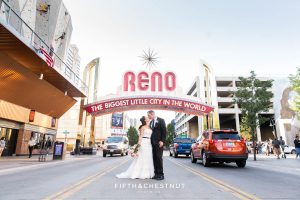 Bride and groom standing under the Reno Arch