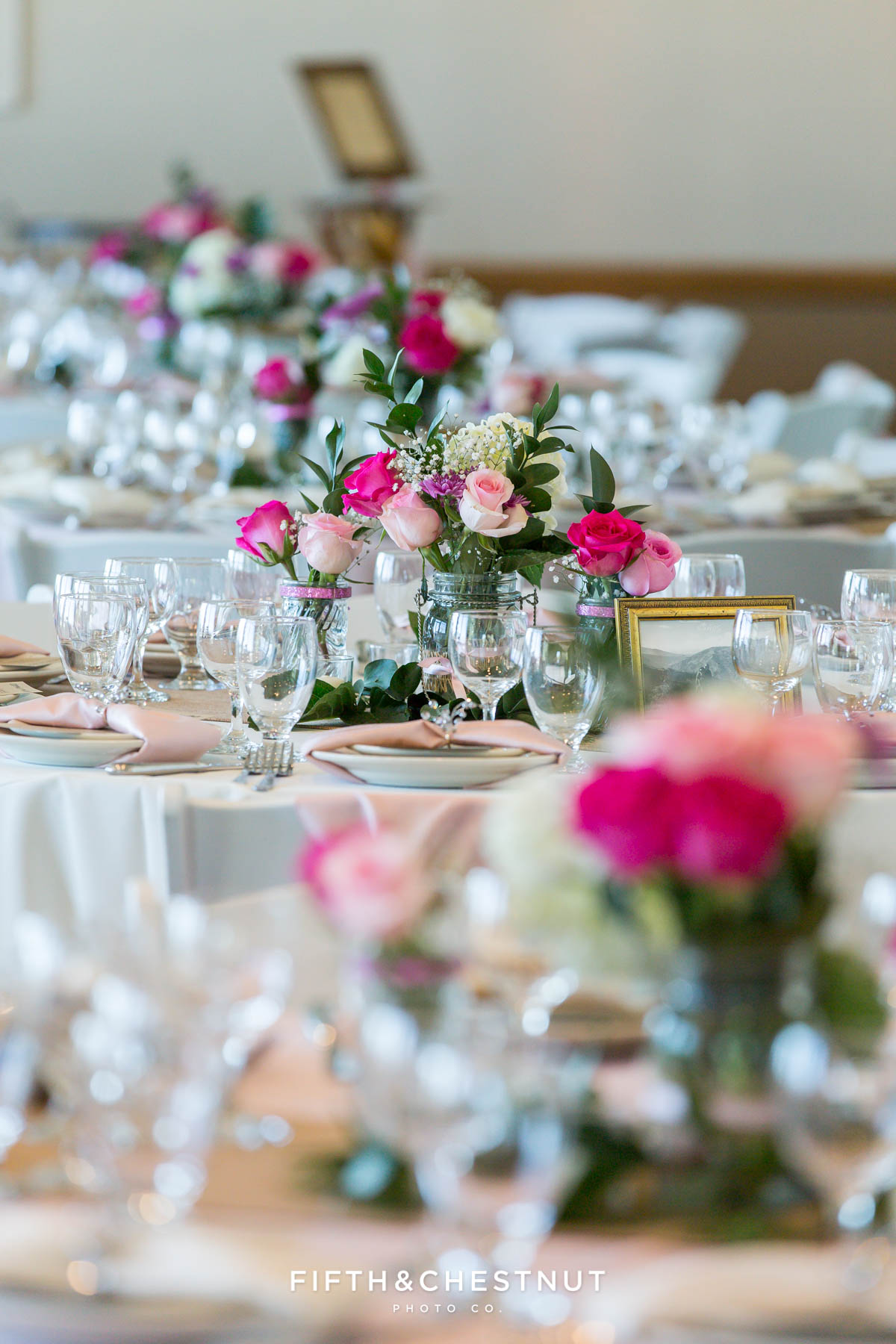 Wedding reception tables with vases of roses and place settings for a North Lake Tahoe Wedding