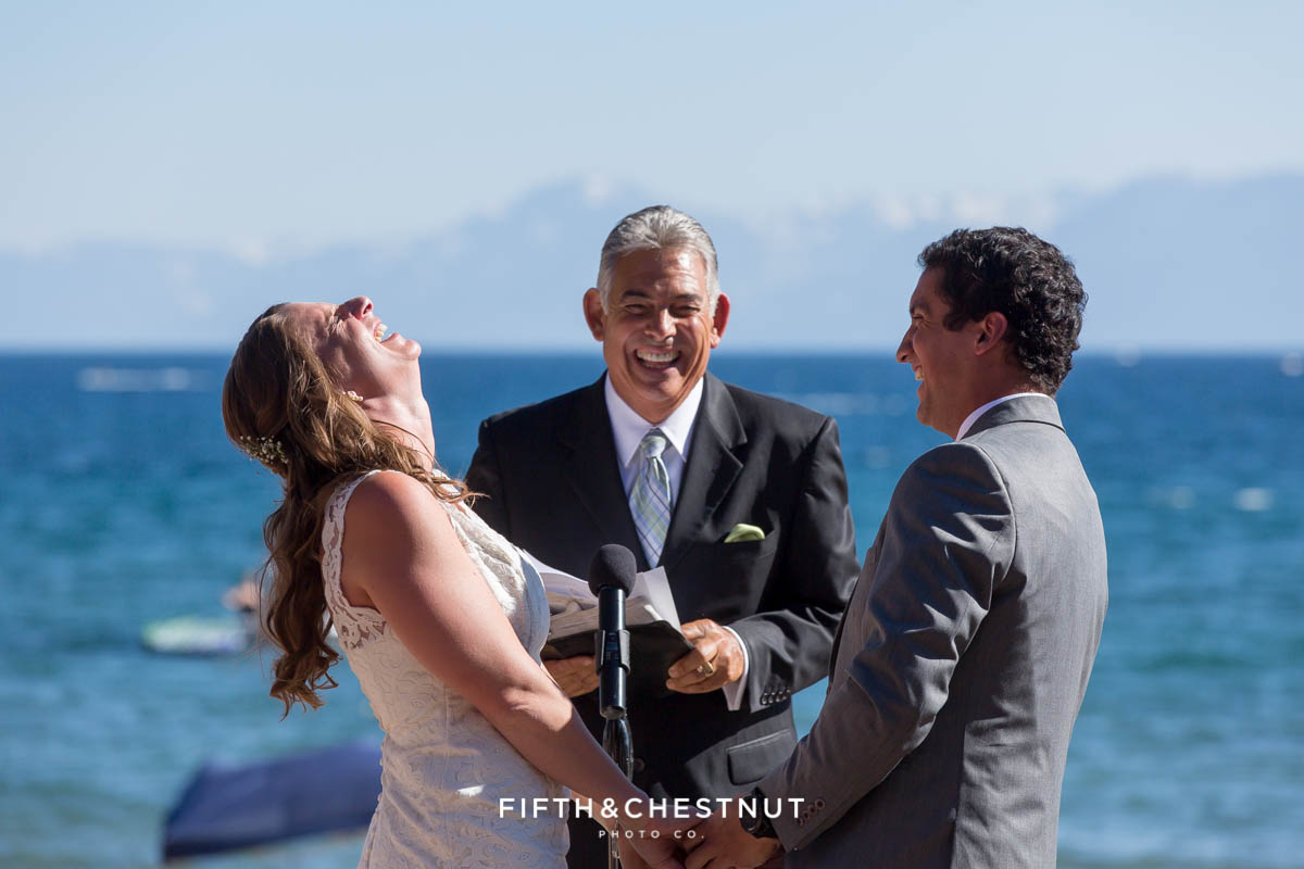 Bride and groom laugh hysterically during wedding ceremony on the beach of lake tahoe