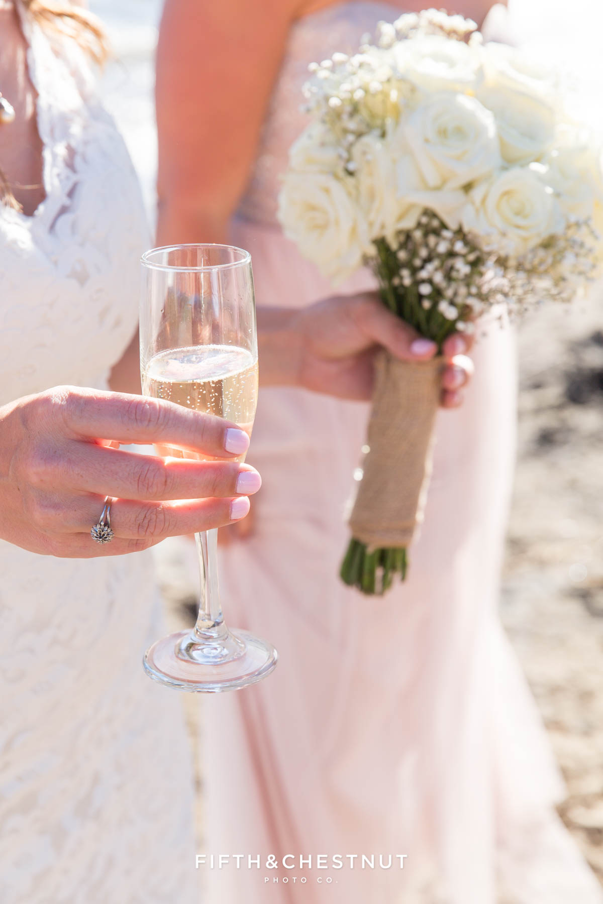 Bride holding bouquet and a glass of sweet champagne on the beach of North Lake Tahoe