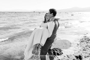 Groom carries bride to the beach for their Tahoe wedding