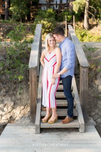 Groom-to-be whispers in his fiance's ear on steps of a dock after their romantic Donner Lake Proposal