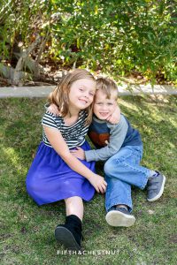 a boy and girl sitting on grass wearing blue pose for Bartley Ranch Portraits by Reno Family Photographer