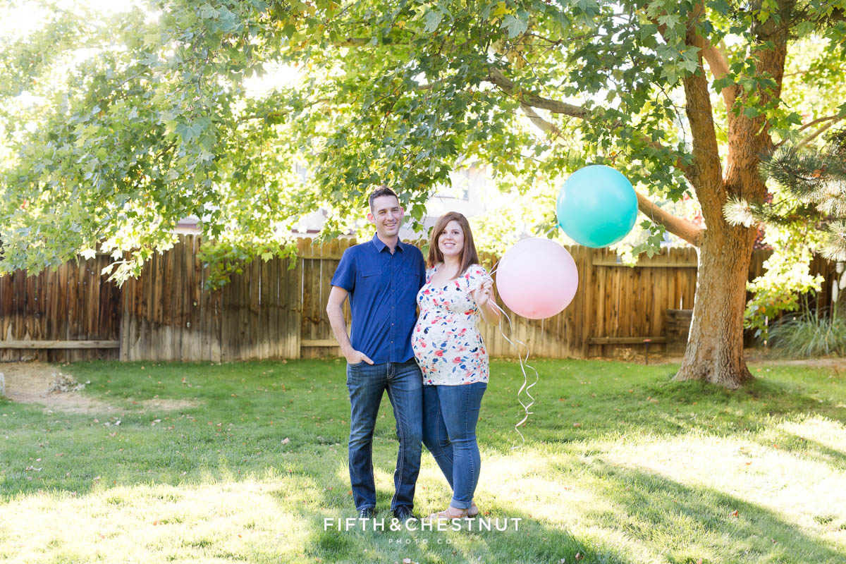 Twin gender reaveal with couple holding a blue balloon and a pink balloon