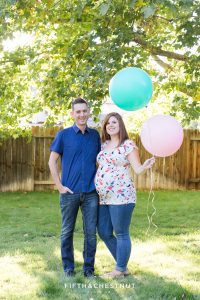 Twin gender reaveal with couple holding a blue balloon and a pink balloon