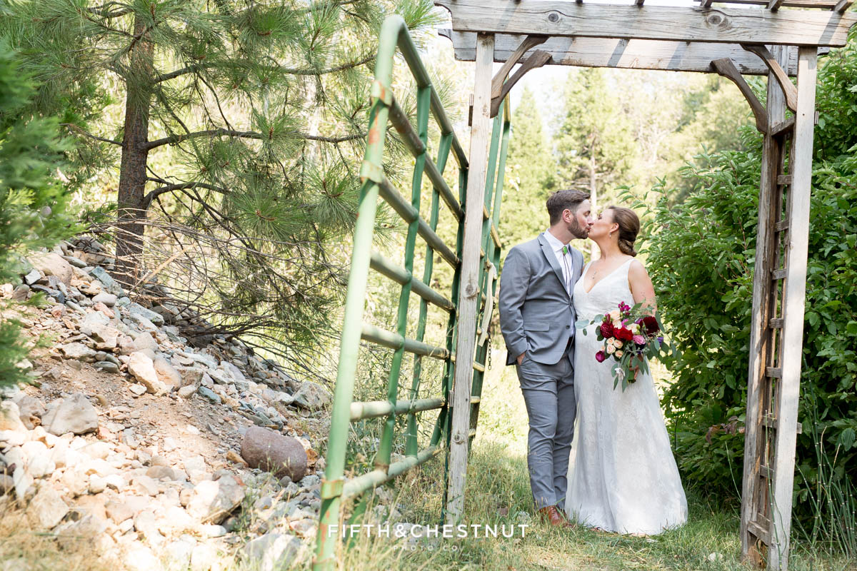 bride and groom kiss under arbor at a bright and summery wedding bouquet for a Greenhorn Creek Guest Ranch Wedding