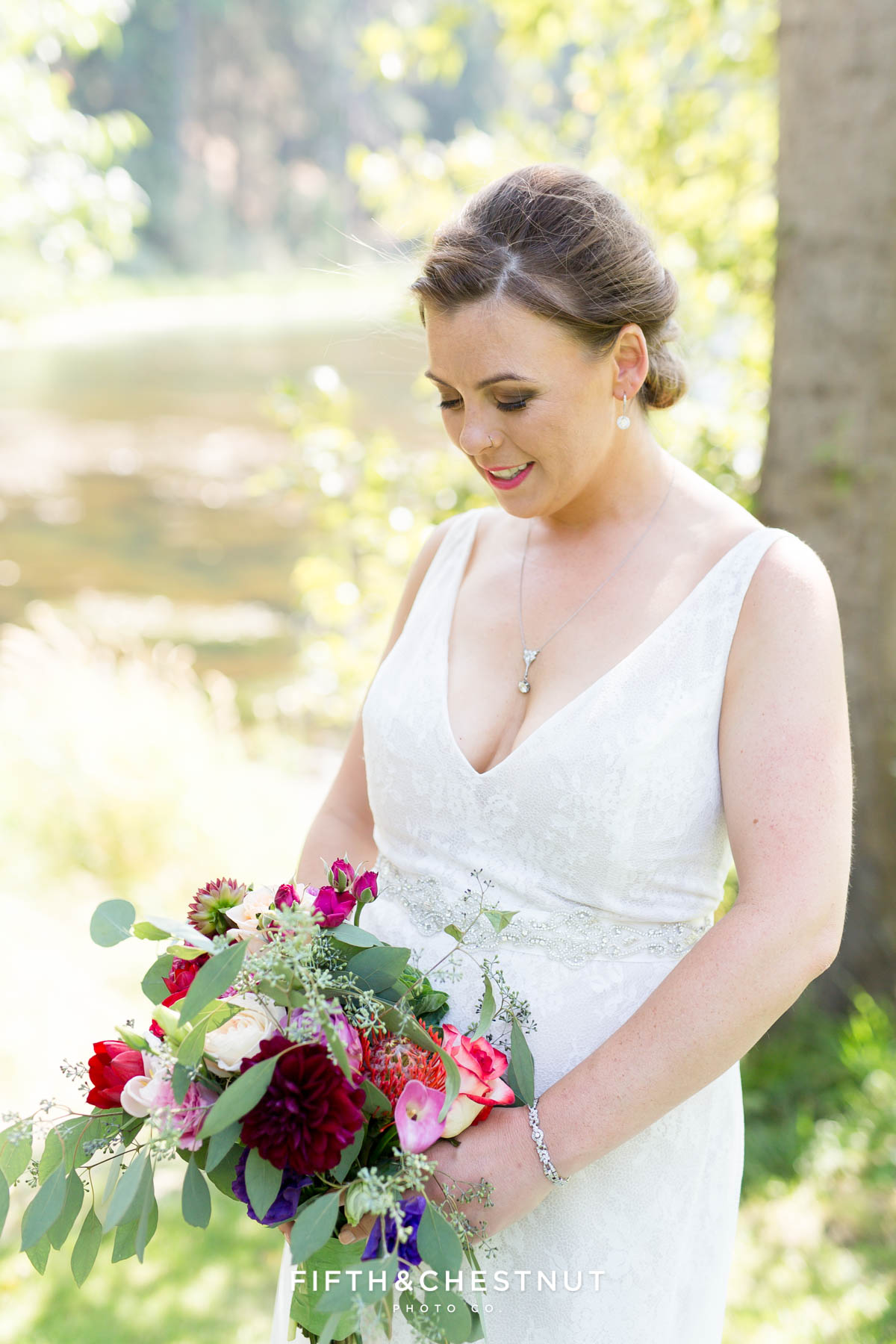 bride looks down at her wedding flowers while wearing a lacy white wedding dress