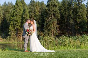bride and groom place their foreheads together for a portrait in front of the lovely pond at their Greenhorn Creek Guest Ranch Wedding