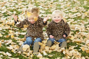 toddlers playing in fall leaves wearing cheetah print jackets for Mayberry Park Portraits