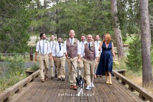 Grooms walk their dog, Cooper, down a wooden path in Truckee before their gay wedding at PJ's at Gray's Crossing