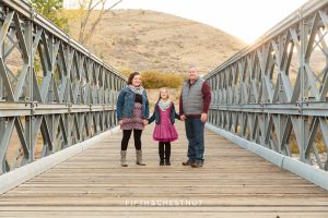 Family of three on a bridge during their Mayberry Park Portraits by Reno Family Photographer