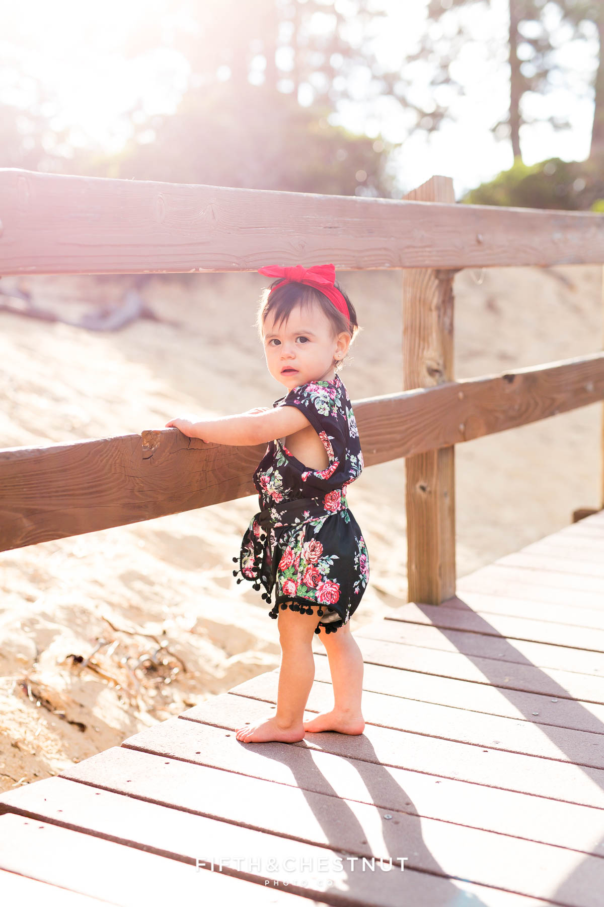 One year old girl wearing a black floral romper for her Fashionable One Year Portraits at Sand Harbor in Lake Tahoe