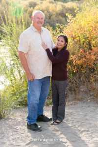 grandparents pose for a photo together in front of the truckee river at mayberry park