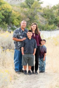 family of four stands in field with rabbitbrush for vibrant fall  portraits at Mayberry Park