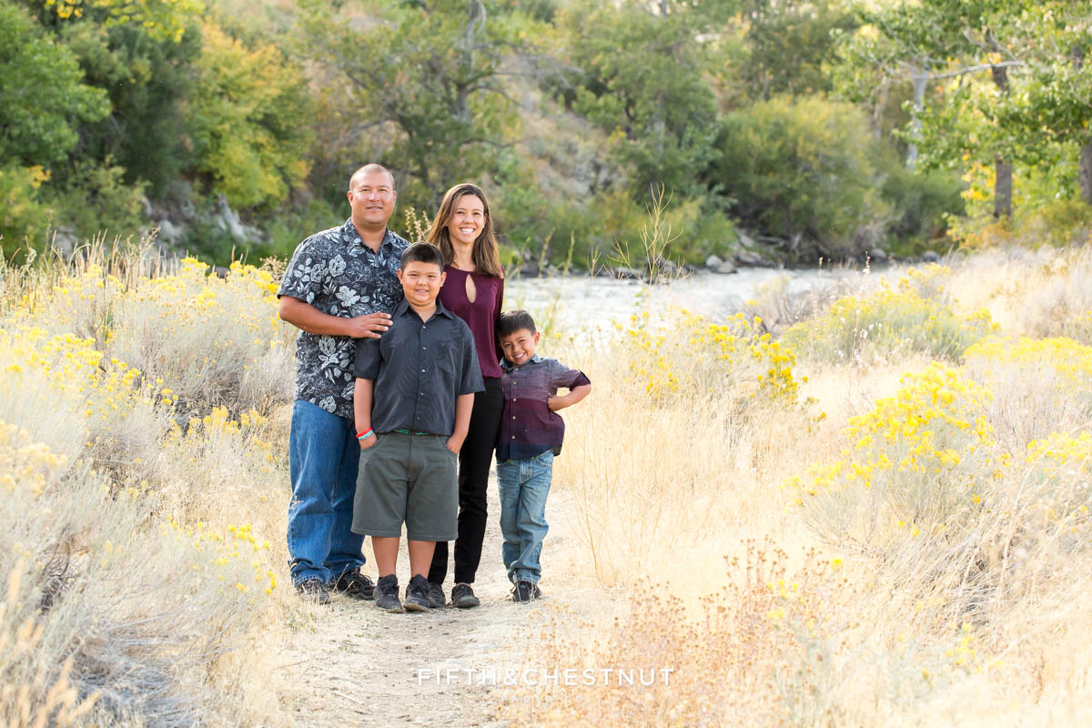 family of four stands in field with rabbitbrush for vibrant fall  portraits at Mayberry Park