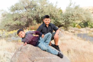two brothers sit on a boulder for vibrant fall  portraits at Mayberry Park