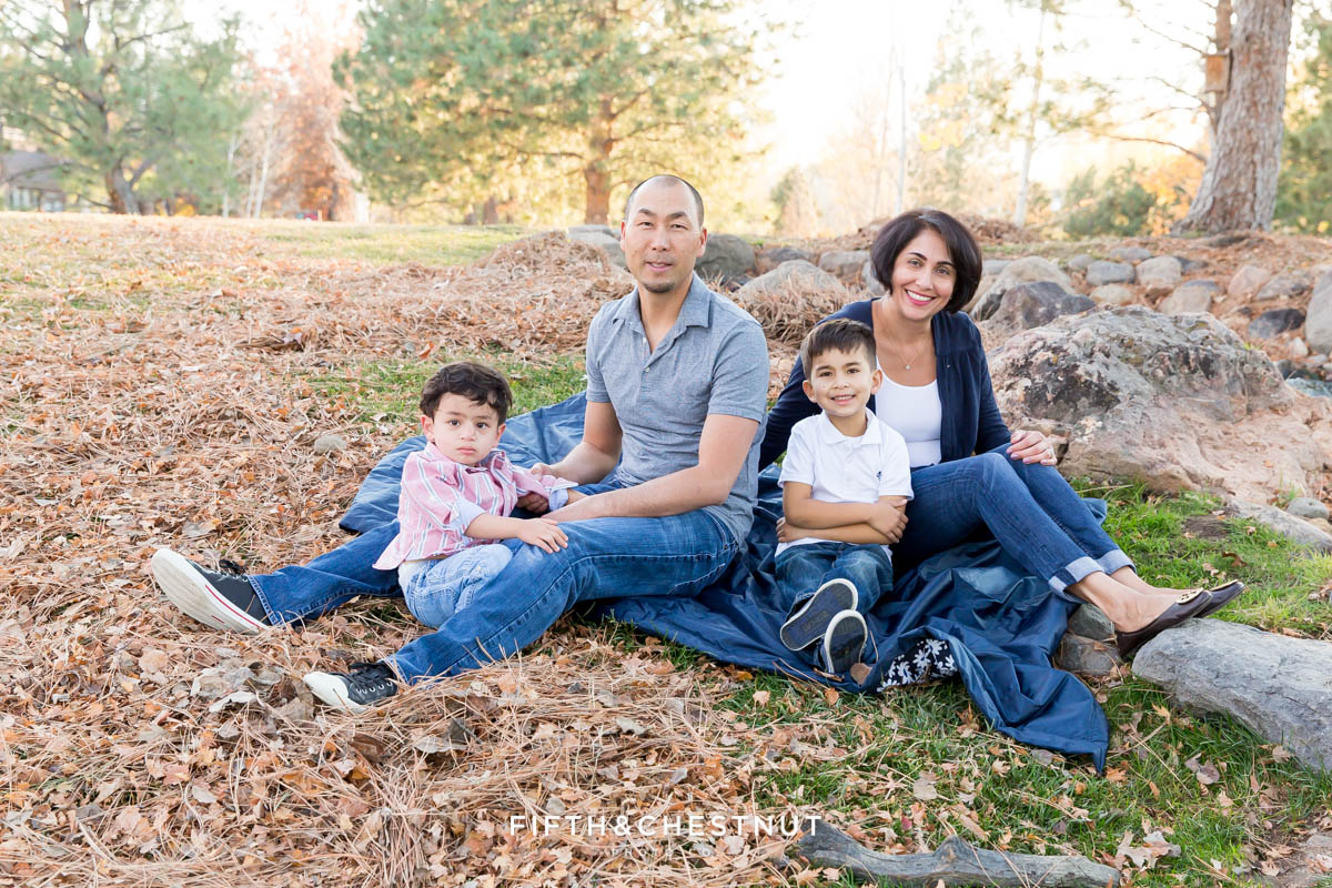 Family of four sits next to waterfall for Caughlin Ranch Family Portraits