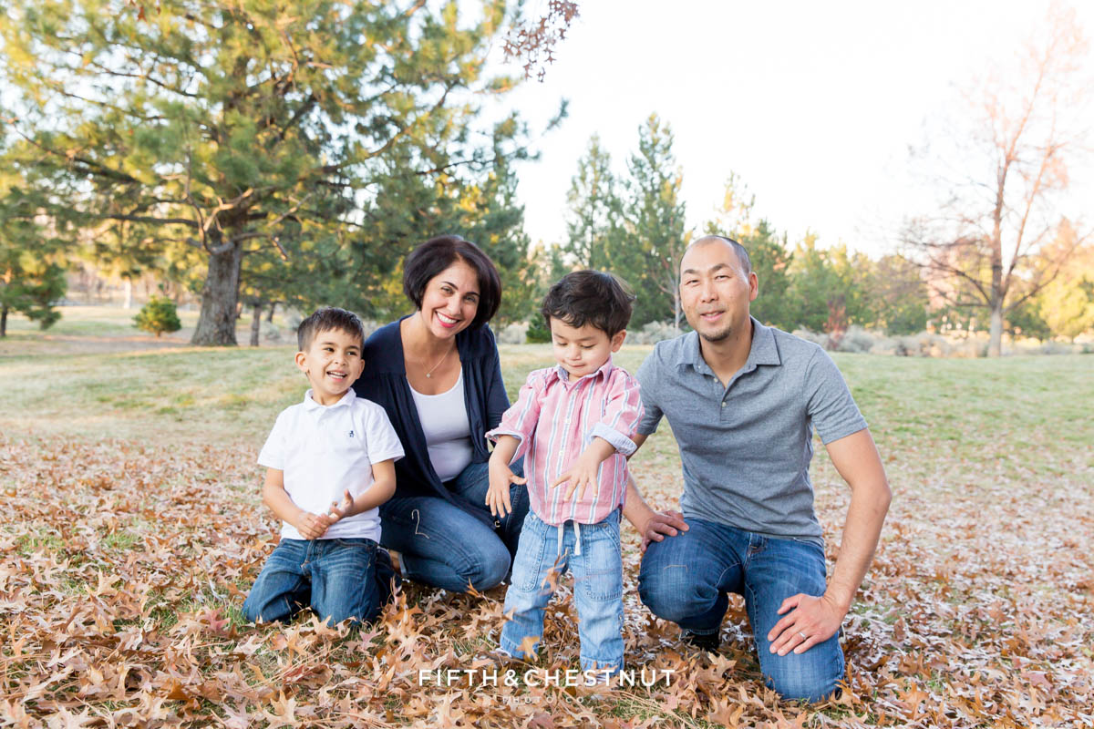 family of four plays with fallen leaves for Caughlin Ranch Family Portraits