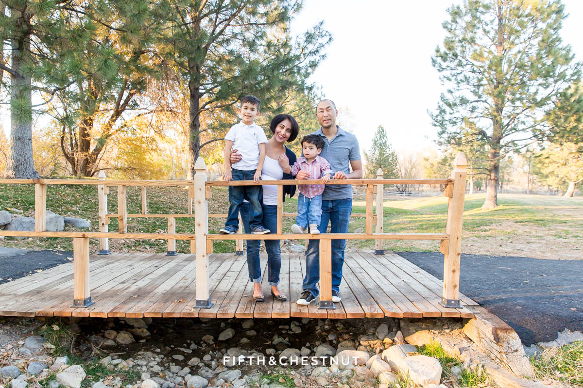 family of four stands on bridge for their Caughlin Ranch Family Portraits