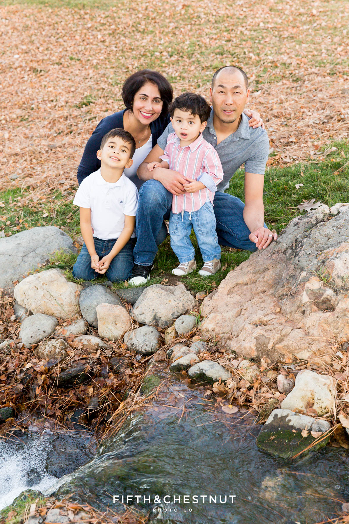 sweet family of four poses near creek for Caughlin Ranch Family Portraits