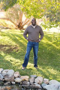 man in brown sweater and jeans poses for his fall family portraits at Caughlin Ranch