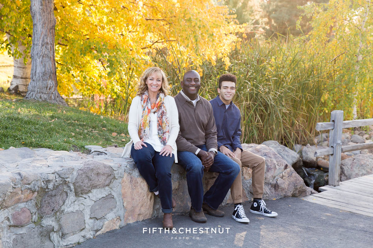 family of three sit on rocks at caughlin ranch for portraits