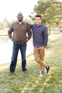 Father and son pose together in front of a pond for fall family portraits at Caughlin Ranch