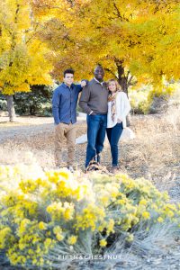 Family of three stands near bright yellow tree for Reno fall family portraits