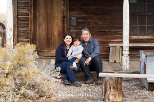 family of three sits on wooden porch for their Adorable Reno Family Portraits