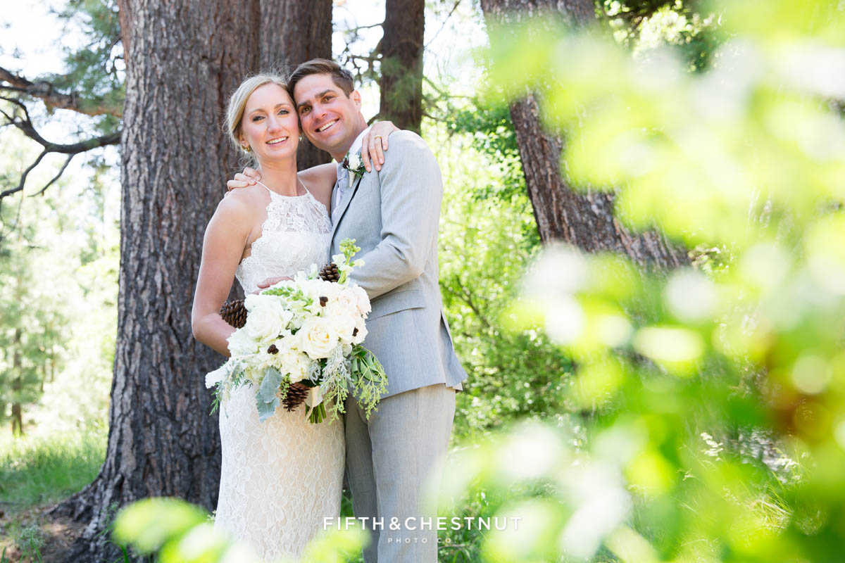 bride and groom embracing with leaves in the foreground