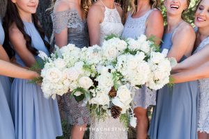 bride and bridesmaids in dusty blue show off their bouquets for a Tahoe wedding