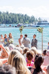everyone laughs during a lake tahoe wedding ceremony with boats in the background