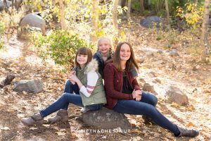 sisters sit on a rock together for Galena Creek Reno fall portraits