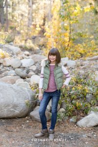 teenage girl in green puffy vest poses in front of rocks for Galena Creek Reno fall portraits by Reno Family Photographer