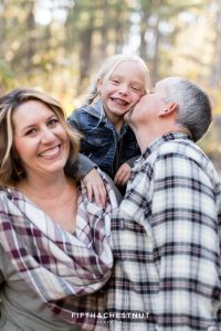 dad kisses daughter on cheek while mom laughs during Galena Creek Reno fall portraits by Reno Family Photographer