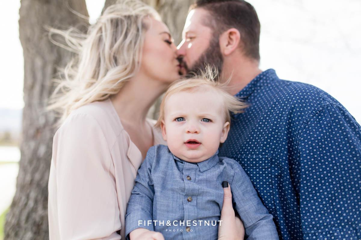 Focus on baby boy while mom and dad kiss in the background for Golf Themed One Year Photos by Reno Baby Photographer