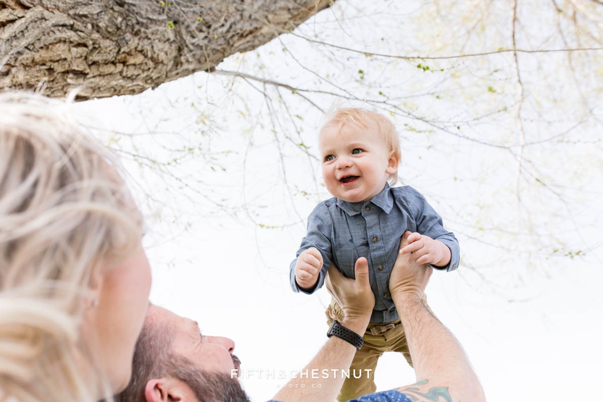 dad holding baby boy up high in the sky for Golf Themed One Year Photos by Reno Baby Photographer