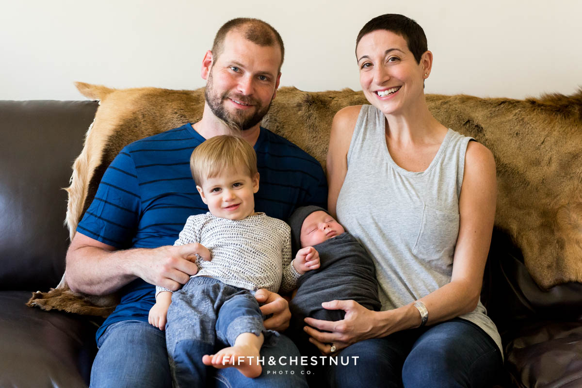 A mom and dad hold their two boys in their laps for a family portrait by Reno Newborn Photographer