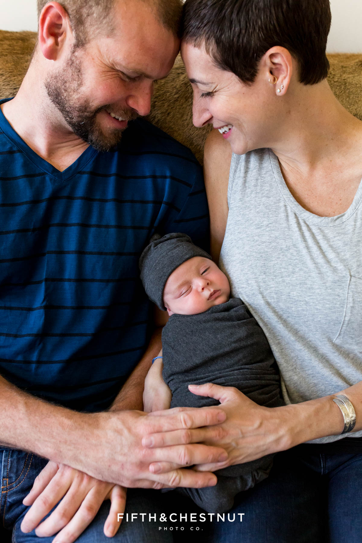 A mom and dad smile with joy as they hold their newborn baby boy for portraits by Reno Newborn Photographer Fifth and Chestnut Photo Co.