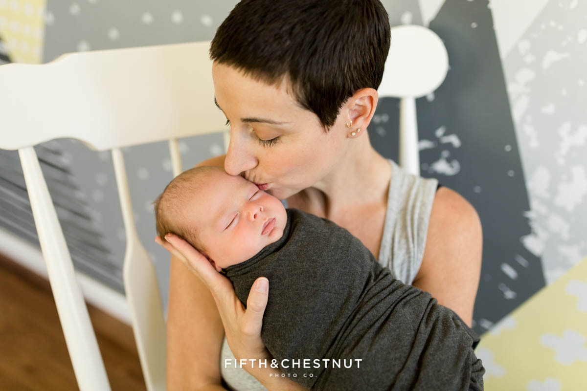 A beautiful mom kisses her newborn son on the forehead during his casual reno lifestyle newborn portrait session
