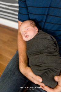 a newborn baby boy lays peacefully in his dad's arms during casual reno lifestyle newborn photos by Reno newborn photographer