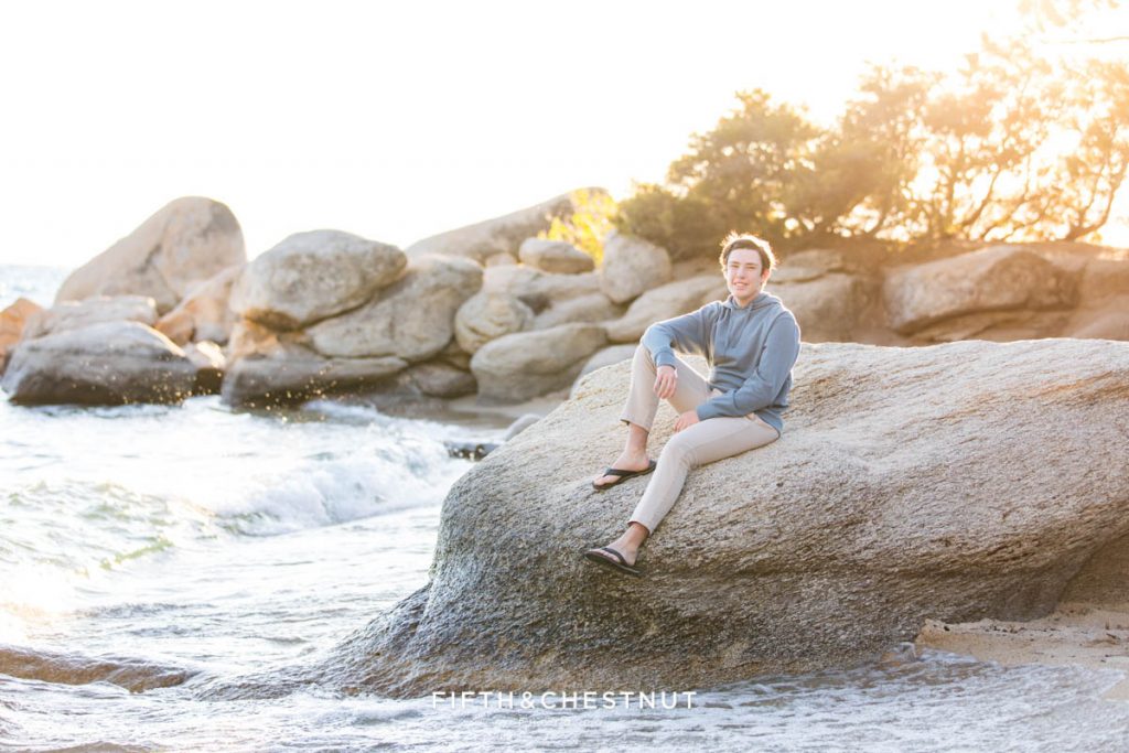 A Bishop Manogue high school student relaxes on a rock at Lake Tahoe  for his Lake Tahoe Senior Portraits at Hidden Beach near Splashing Waves during summer.