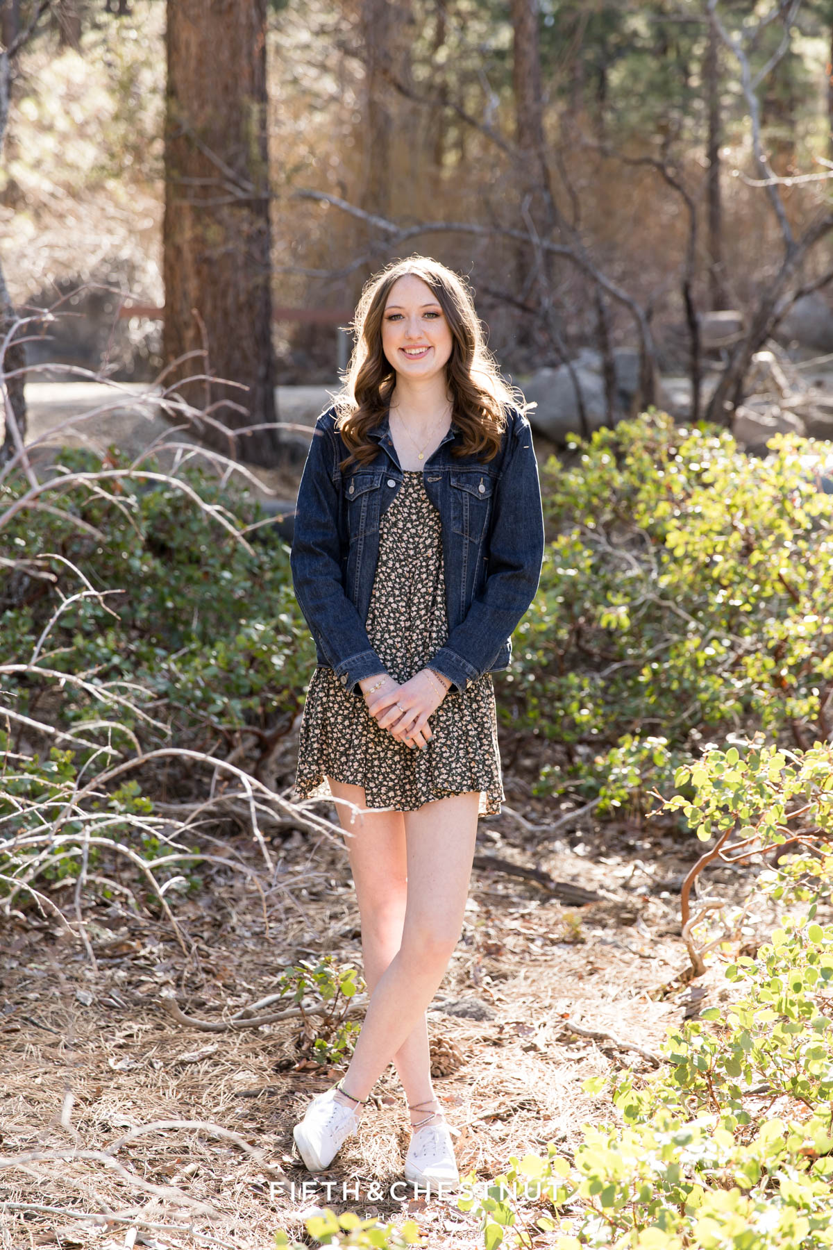 Senior student standing in front of manzanita with hands clasped