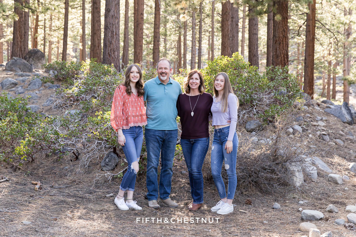 a family stands with their senior student for a family photo during her forest high school senior portrait session with a Reno high school senior photographer