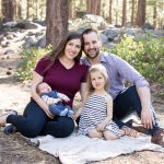 Family of four sitting on a gray picnic blanket for spring outdoor newborn portraits