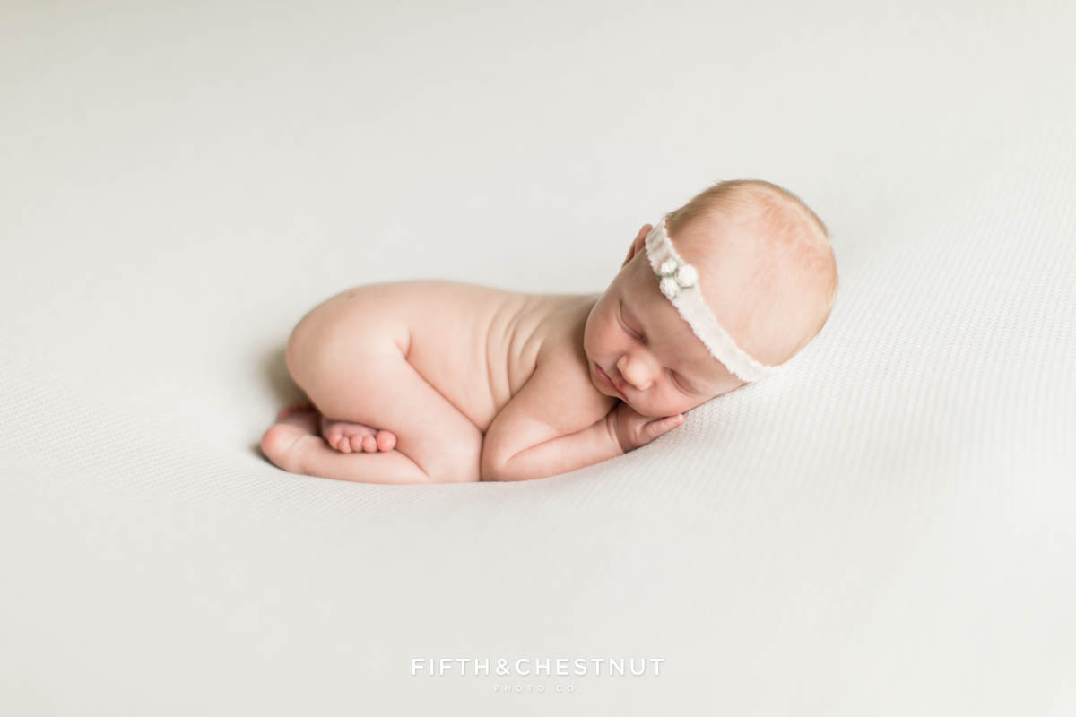 a darling baby girl sleeps peacefully with an adorable headband on her head during her reno newborn twin photos by Reno Family Photographer