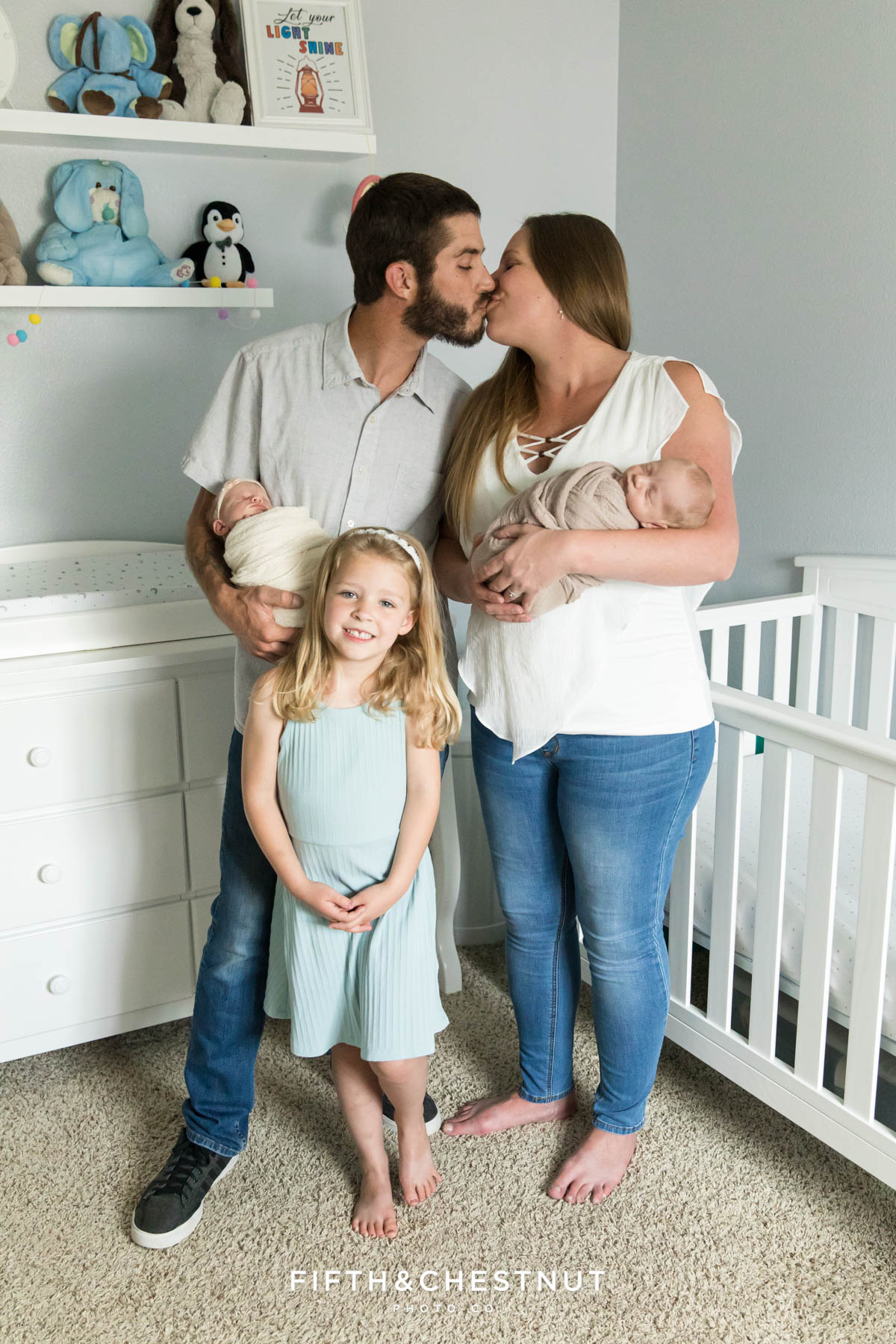 A mom and dad of twins kiss while they hold their new babies