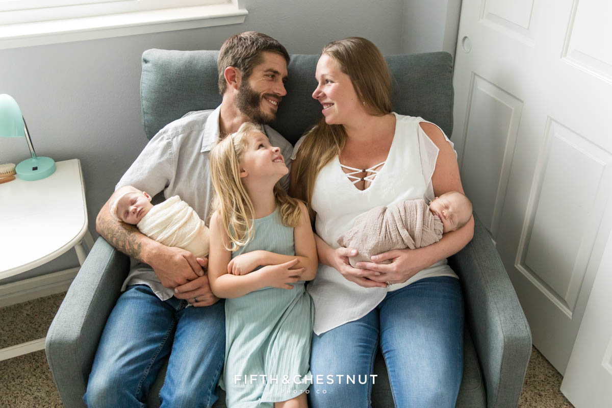 Neutral newborn twin photos of a family laughing together in a double rocking chair