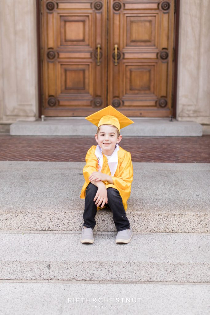 Kindergarten Cap and Gown Portraits of a young boy wearing a gold gown, gold cap and a white sash that says "kindergarten graduate" at UNR in the Spring by Reno Child Photographer