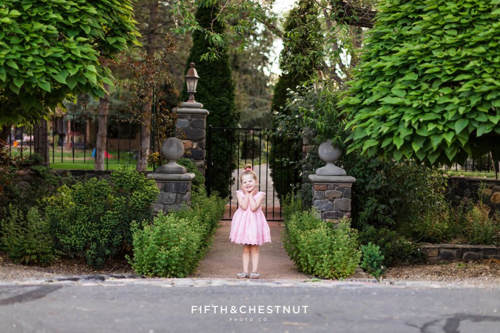 A little girl stands in front of a majestic gate during her sprint wildflower portrait session by reno child photographer